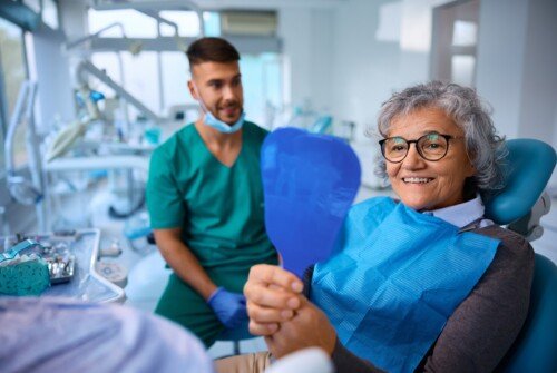 Satisfied,Senior,Woman,Using,Mirror,While,Checking,Her,Teeth,After
